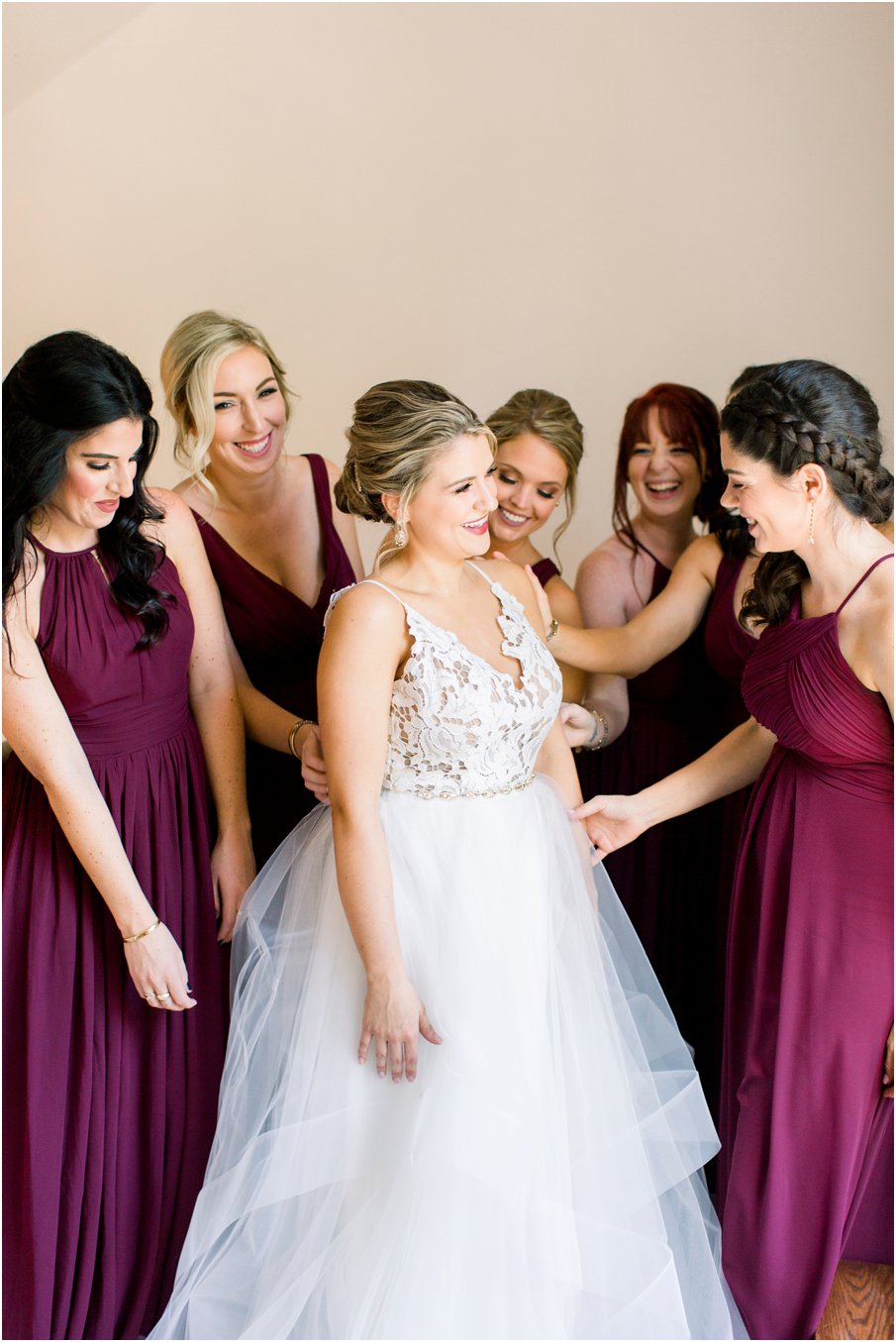A Hayley Paige bride getting ready with all her bridesmaids at Rust Manor House in Leesburg, Virginia. Bridesmaids wearing burgundy dresses