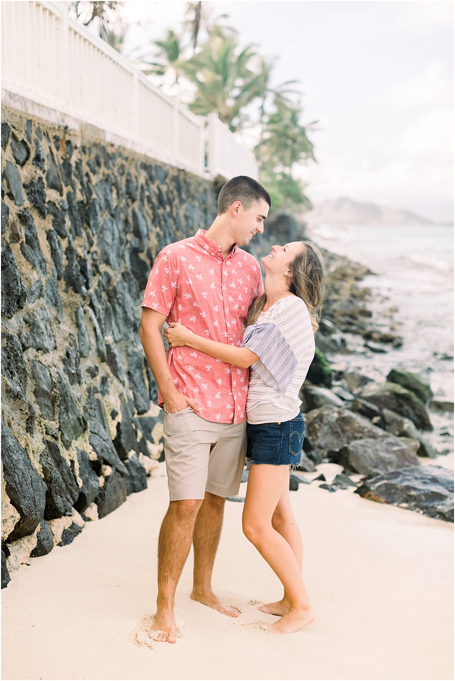 An Oahu based couple's Lanikai beach engagement session. Beautiful palm trees, rocks, and a calm ocean.