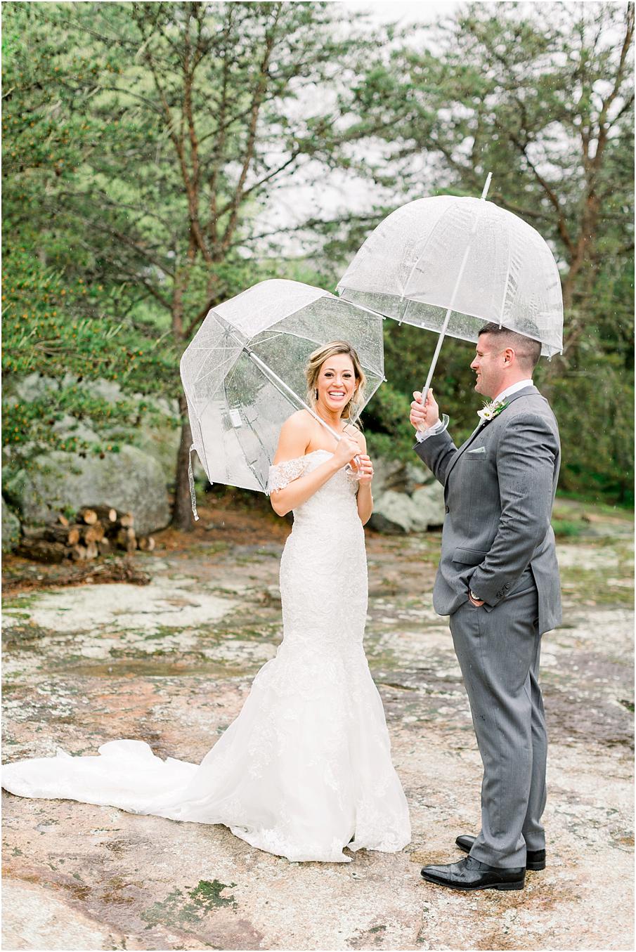 Bride and groom under bubble umbrellas in the rain for their first look at The Mill at Fine Creek
