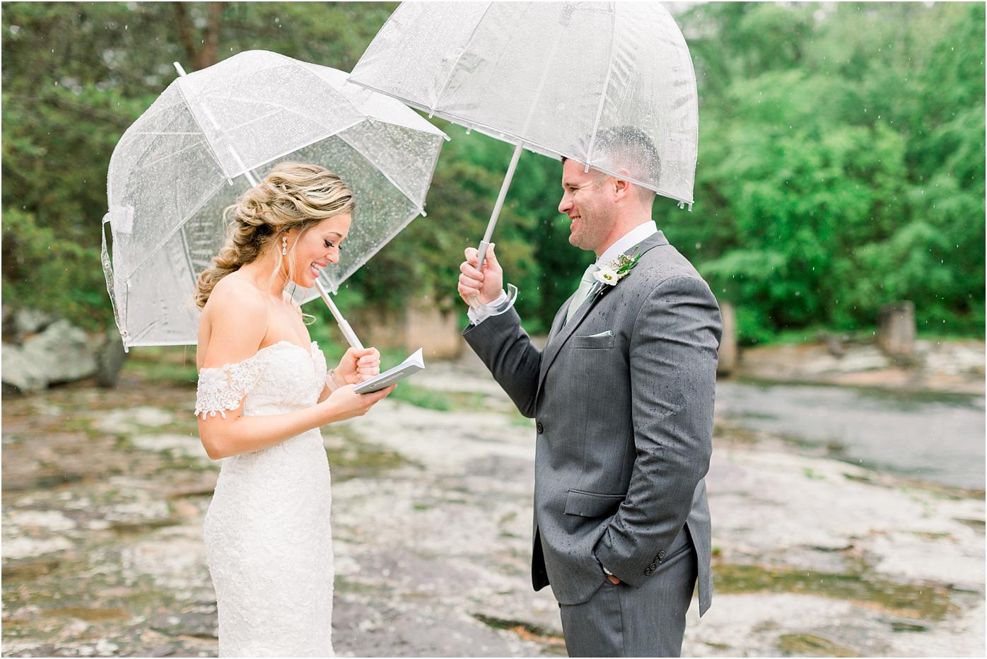 Bride and Groom read vows to one another before their Mill at Fine Creek wedding ceremony under umbrellas.