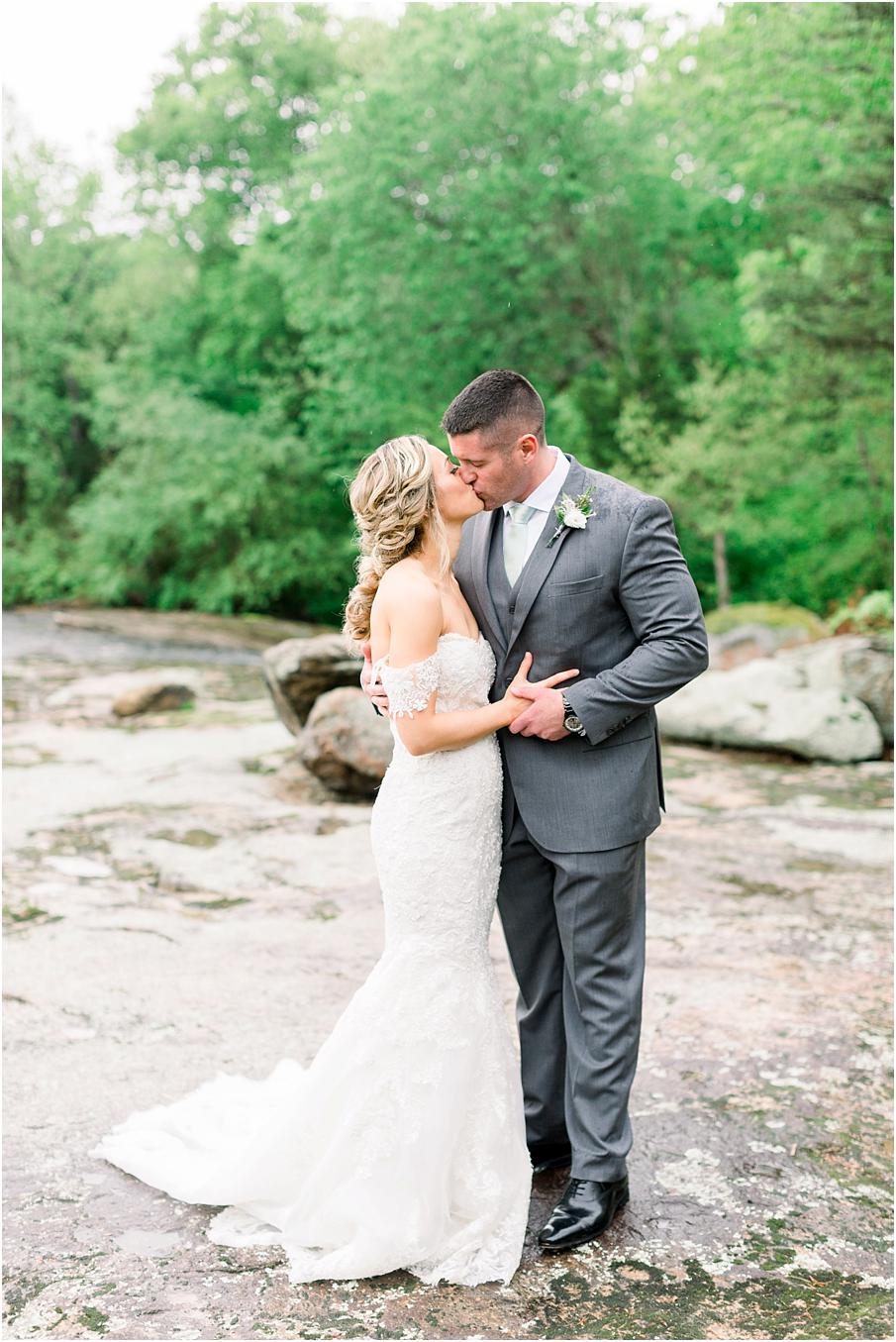 Mill at Fine Creek Wedding photo with bride and groom kissing in the rain on the rocks near the James River