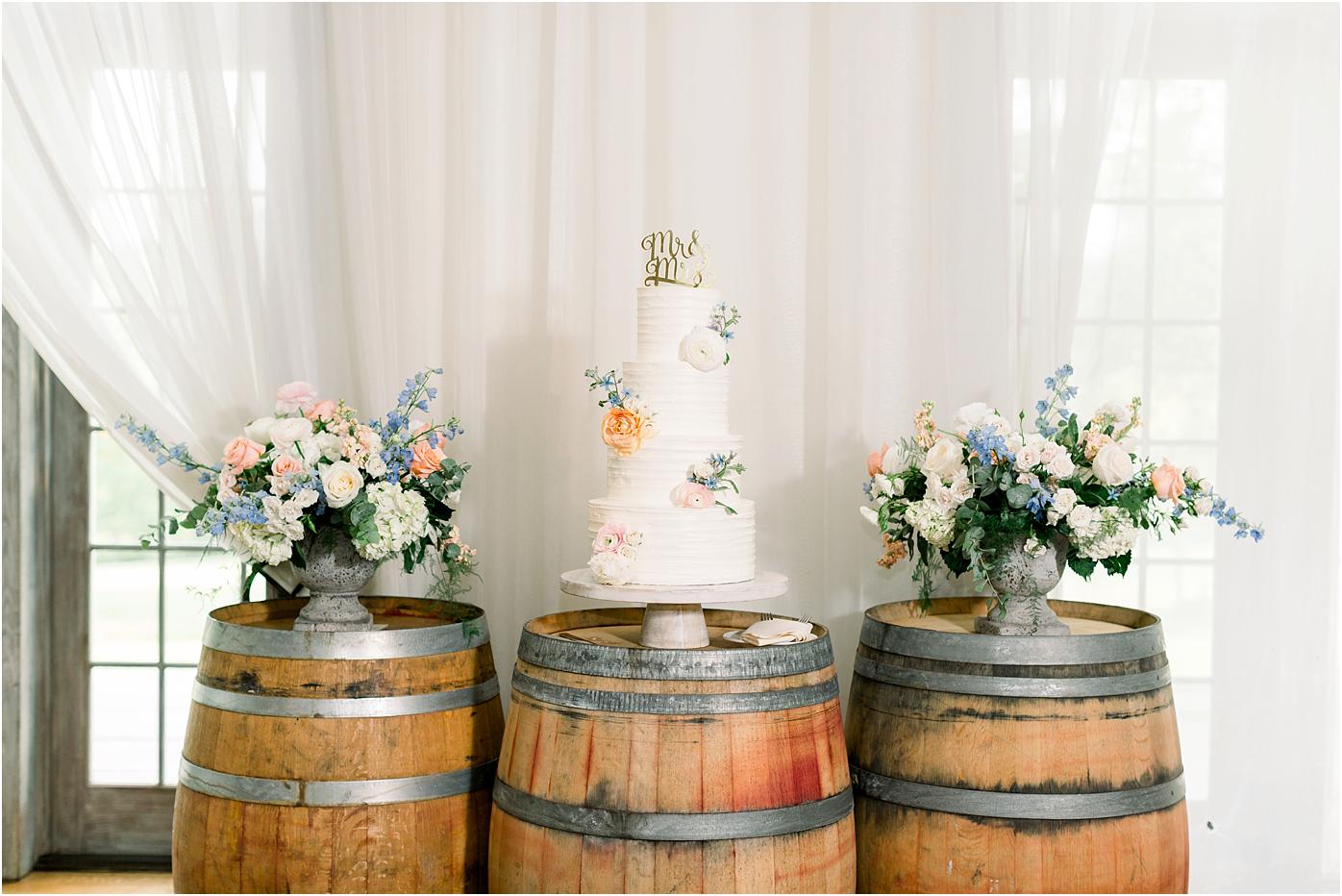 A stunning three tiered vanilla frosted wedding cake on a wine barrel for the bride and groom's Veritas Winery wedding