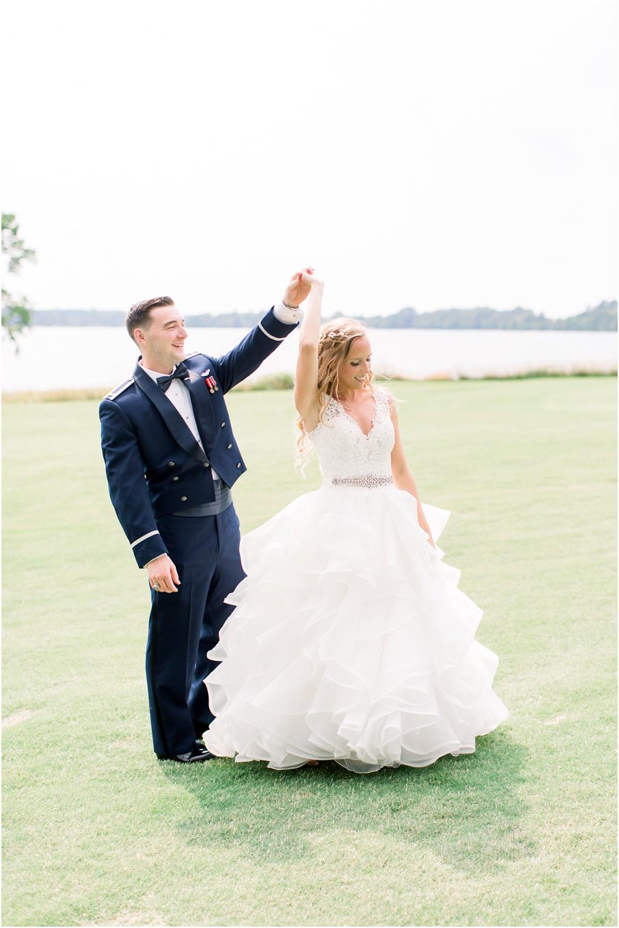 Groom twirls bride during their first look at Two Rivers Country Club. Groom in his military uniform and bride in ruffled, white wedding dress.
