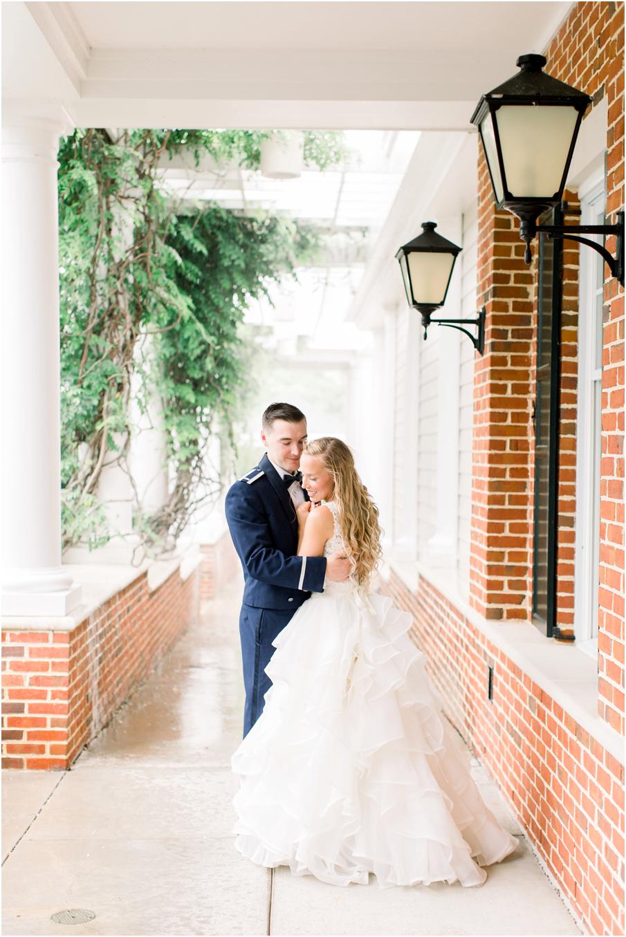 Bride and groom cuddle under the porch at Two Rivers Country Club as it pours down rain outside