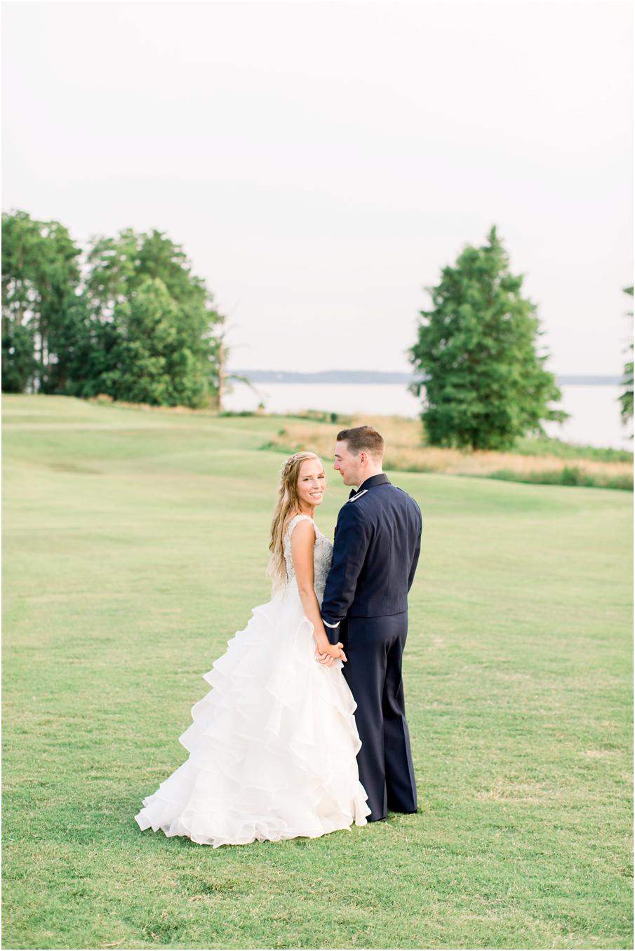 Sunset photo of bride and groom with water, trees, and tall grass in the background at Two Rivers Country Club