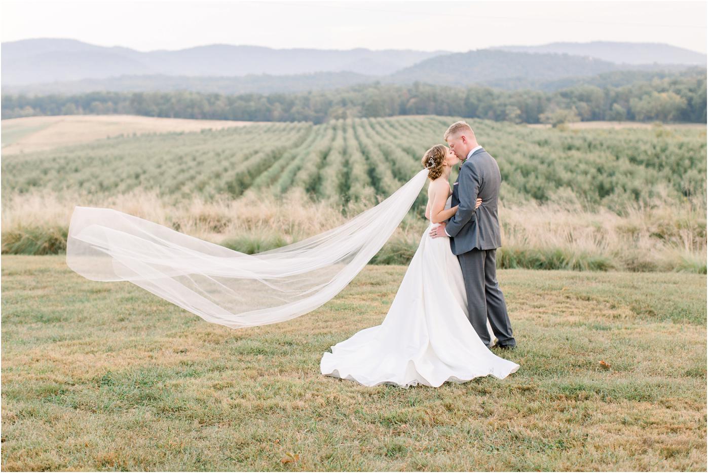 Bride and Groom Pharsalia wedding portrait with a veil toss, mountain backdrop and a kiss